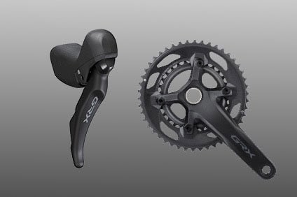 Shimano GRX bike shifter and crankset on a grey background