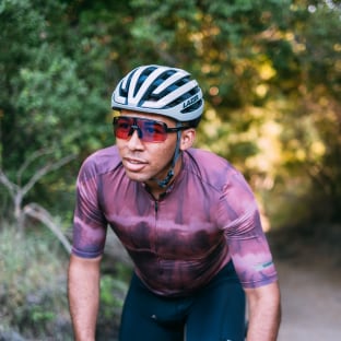 Cyclist wearing a helmet and sunglasses riding on a forest trail