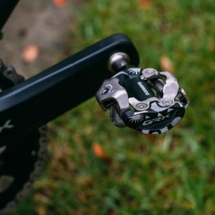 Close-up of a bicycle pedal with grass in the background.