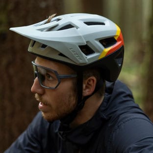 Man wearing a white and black bicycle helmet and protective glasses in a forest