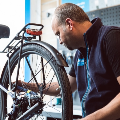 En cykelmekaniker undersøger baghjulet på en cykel på et værksted