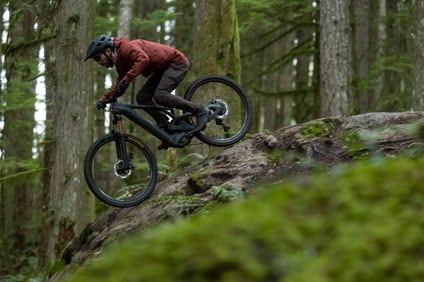 Mountain biker riding down a rocky slope in a forest