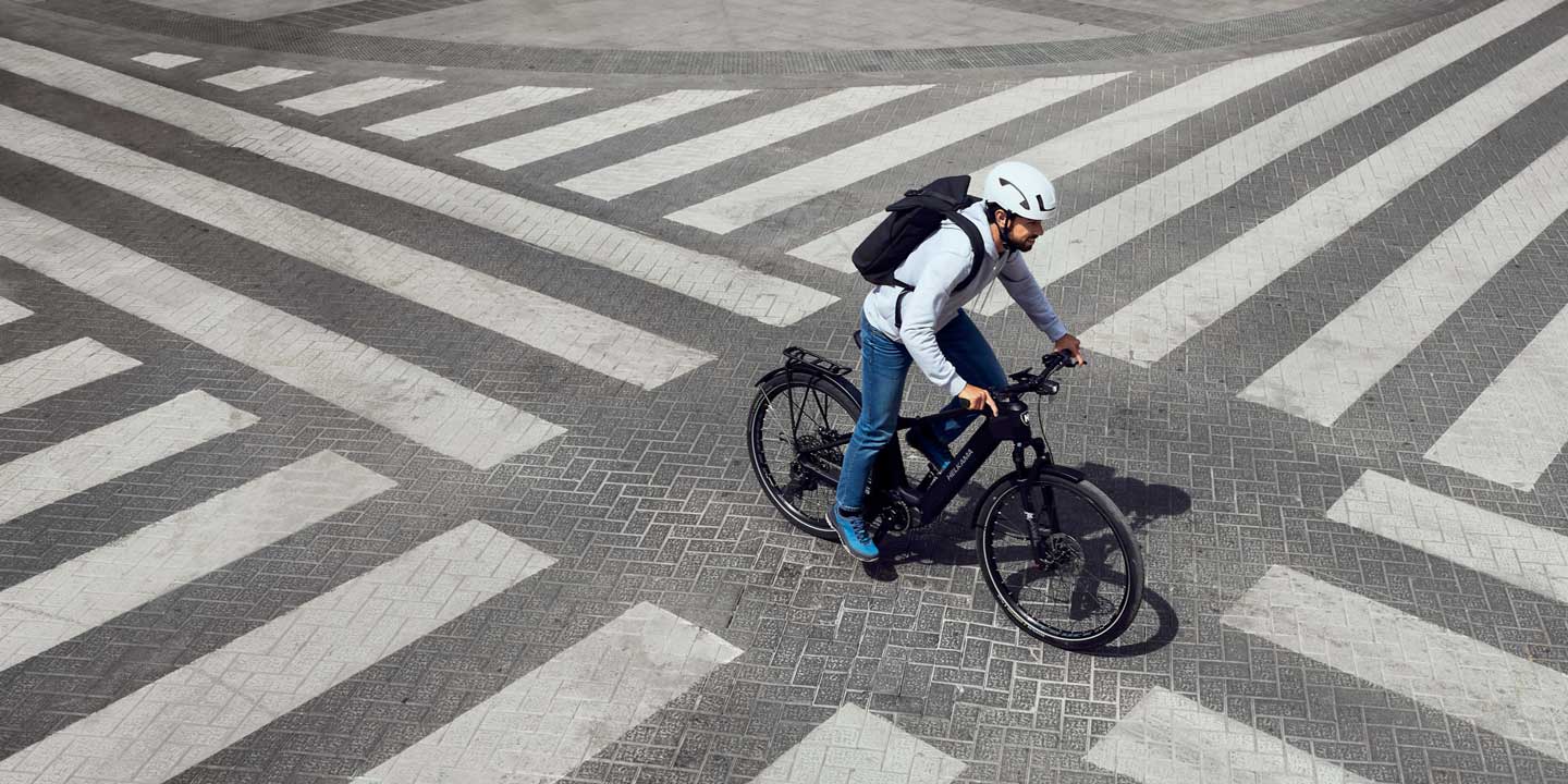 Person riding a bicycle through a large crosswalk with multiple zebra stripes