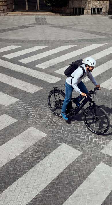 Person riding a bicycle through a large crosswalk with multiple zebra stripes