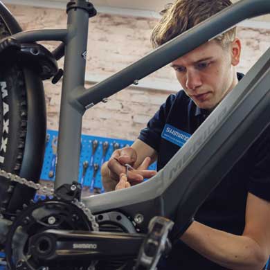 A bike mechanic working on a grey bicycle in a workshop