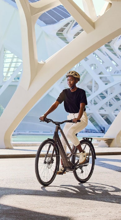 Person riding a bicycle under modern architectural structures
