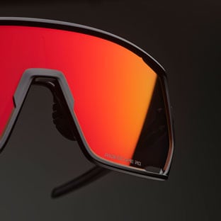 Close-up of sports sunglasses with red-orange lens on dark background