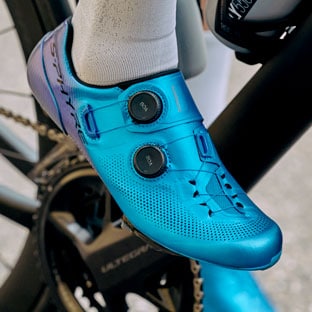 Close-up of a cyclist's foot wearing a blue cycling shoe on a bicycle pedal