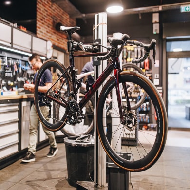 Bicycle in repair stand at a bike shop with mechanic in background.