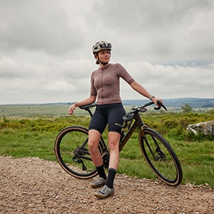 Cyclist riding a bicycle on a dirt trail with a rocky background