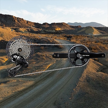 Di2 GRX bicycle drivetrain on a deserted road with mountains in the background