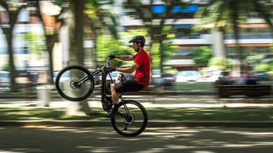 Person macht einen Wheelie mit einem Fahrrad in einem Park.
