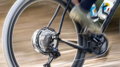 Close-up of a spinning bike wheel and pedals in motion on a dirt path