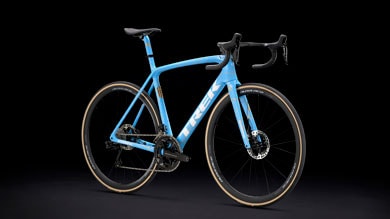 Blue Trek road bike with black handlebars on a black background