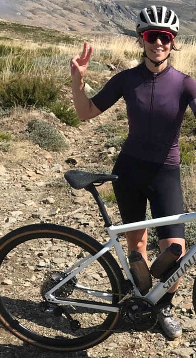 Radfahrer posiert mit Fahrrad auf einem felsigen Pfad in bergiger Landschaft.