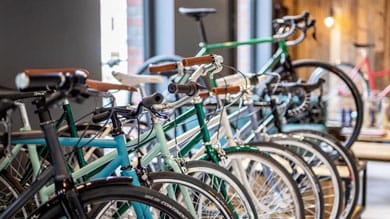 Rząd kolorowych rowerów z brązowymi kierownicami w sklepie rowerowym.