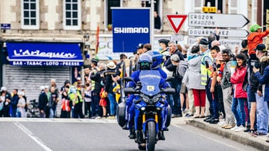 Moto avec logo Shimano entourée de spectateurs dans la rue.