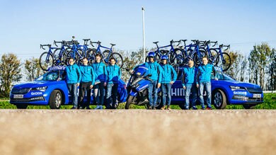 Équipe en vestes bleues avec véhicules d’assistance et vélos.