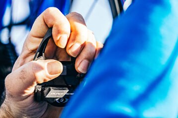 Personne ajustant une pédale de vélo avec un vêtement bleu au premier plan.
