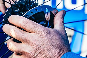 Mains ajustant les rayons d'une roue de vélo.
