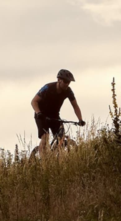 Deux cyclistes sur une colline herbeuse au crépuscule.