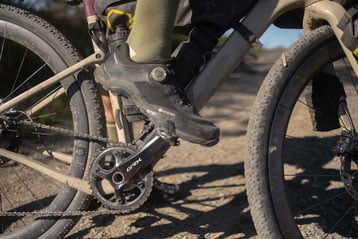 Close-up van de voet van een fietser op een GRX-pedaal op een grindpad.