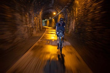 Fietser fietst door een verlichte tunnel.