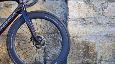 Roue avant de vélo contre un mur en pierre.