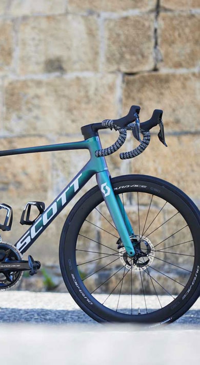 Vélo de route Scott contre un mur en pierre.