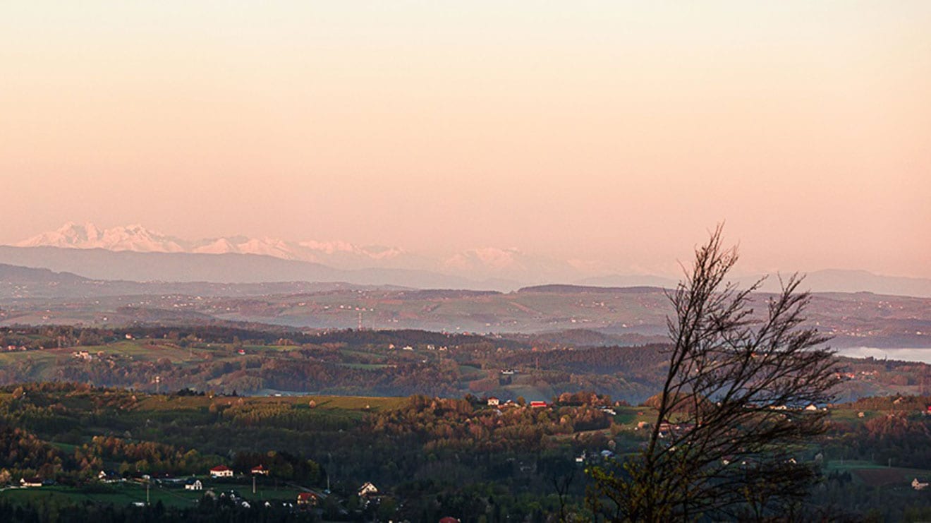 Panoramiczny widok na wieś z odległymi górami o zachodzie słońca.