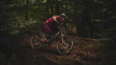 Mountain biker riding through a forest trail in protective gear