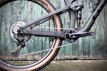 Close-up of a mountain bike chain, gears, and tire against a wooden background