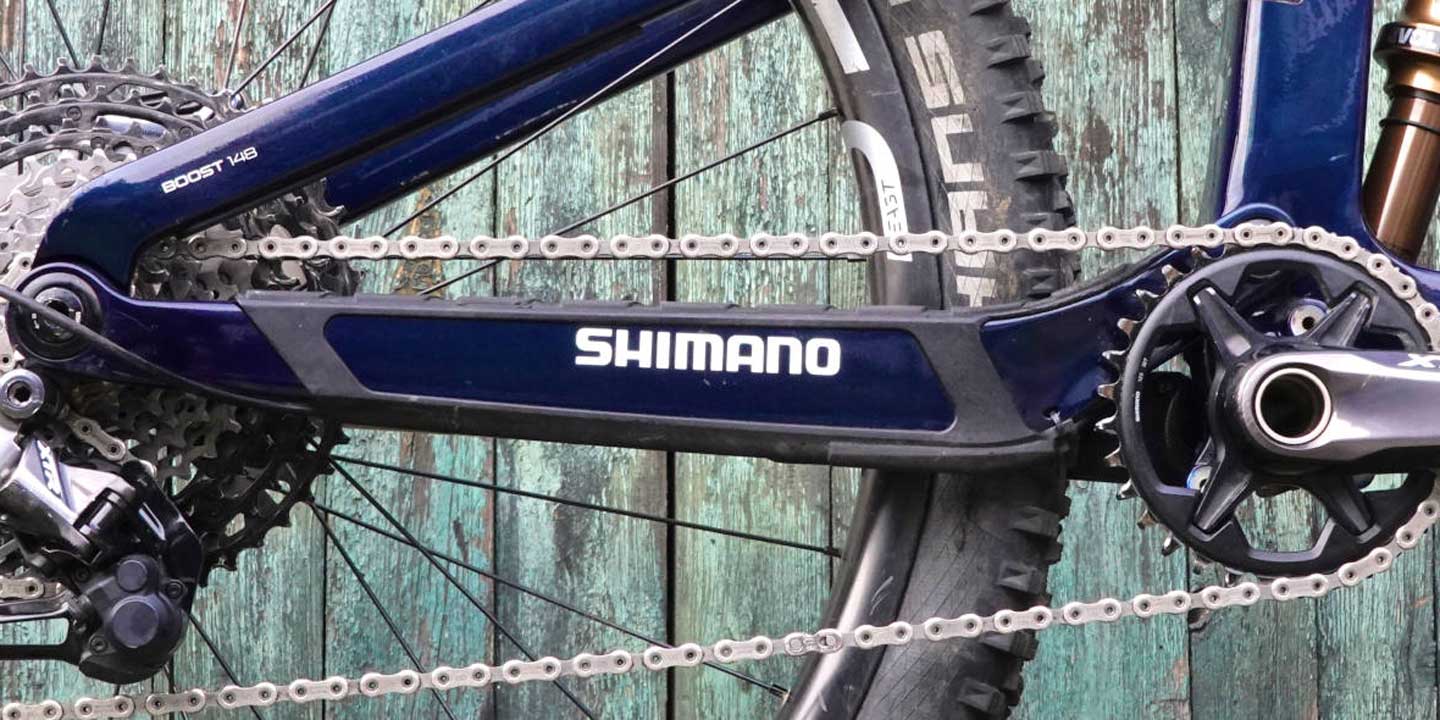 Close-up of Shimano bike chain and gears against a rustic wooden background