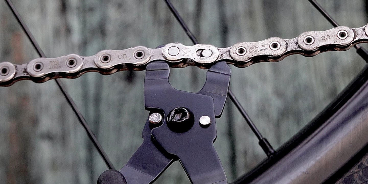 Close-up of bicycle chain with a chain tool attached for maintenance