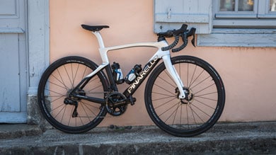 Modern Pinarello road bike leaning against a pastel pink wall with windows on either side.