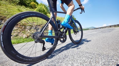 Cyclist riding a road bike uphill with a scenic background