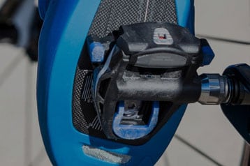 Close-up of a bicycle pedal and cleat on a blue cycling shoe