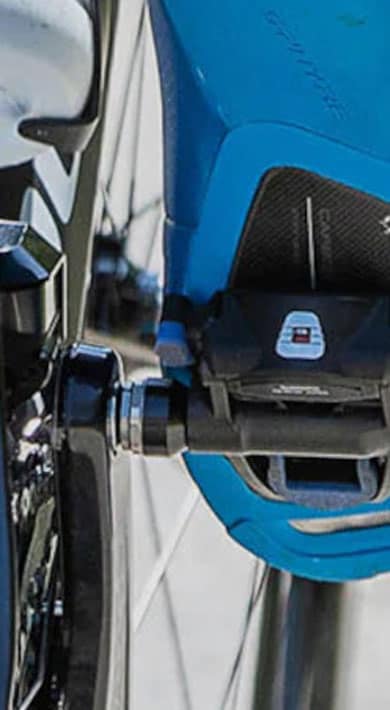 Close-up of a cyclist's foot on a pedal with blue socks and bike gears in view