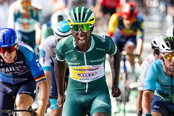 Cyclist in green jersey leading during a race with other cyclists close behind.