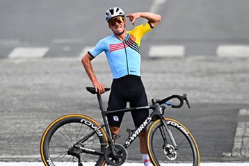 Cyclist in colorful jersey poses with bike on road