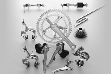 Bicycle components including chain, brakes, and crankset arranged on a gray background.