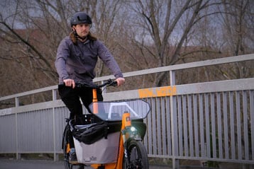 Person fährt mit einem Lastenrad auf einem Brückenweg.