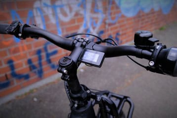 Fahrradlenker mit Digitalanzeige in städtischer Umgebung.