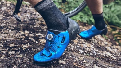 Radfahrer mit blauen Fahrradschuhen auf einem Waldweg