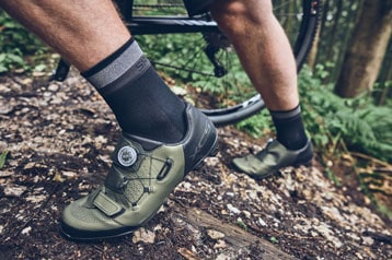 Person mit grünen Fahrradschuhen auf einem Waldweg