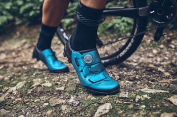Nahaufnahme blauer Fahrradschuhe eines Radfahrers auf einem Trail
