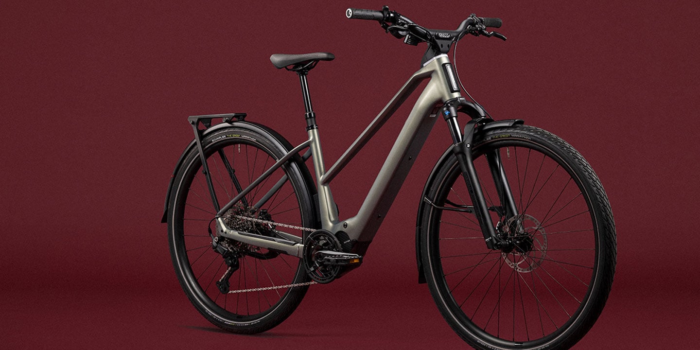 Gray electric bike with a rear rack against a maroon background