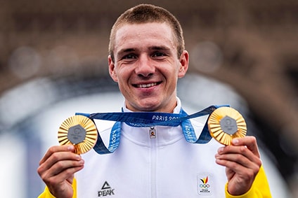 Athlete holding two medals while smiling, with the Eiffel Tower in the background