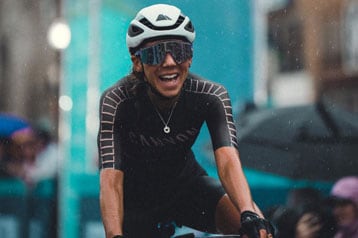 Radfahrer lächelt im Regen während eines Rennens, Nummer 236 am Fahrrad.