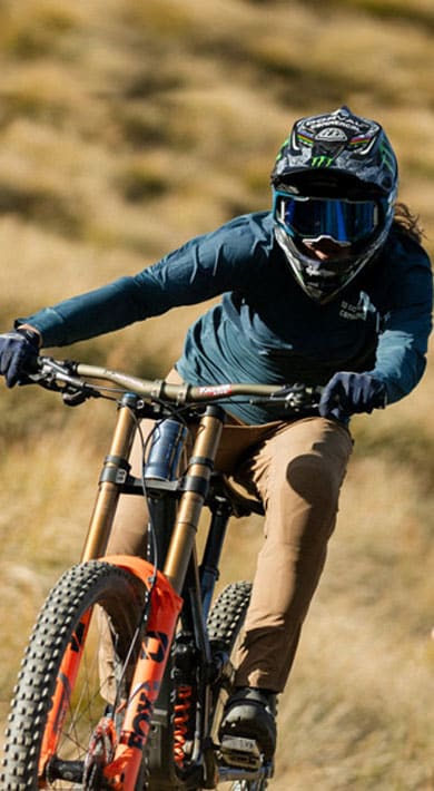 Two cyclists mountain biking downhill on a grassy terrain.